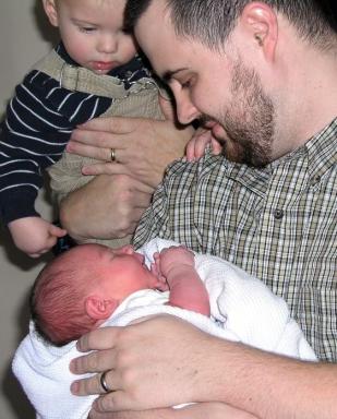 Paul holds Owen while Logan looks on